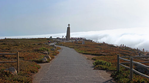 Footpath leading towards lighthouse against sky