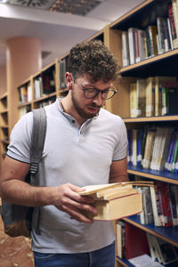 A young man is reading a book in the university library