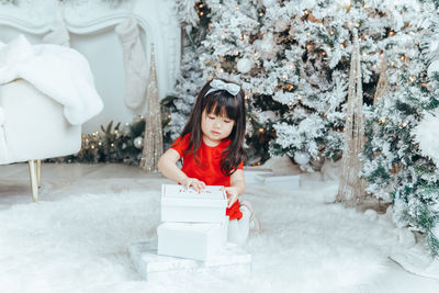 Cute girl sitting by christmas gift at home