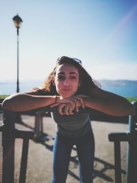 Portrait of smiling young woman standing against clear sky