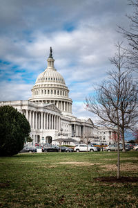 Side view of capitol building in washington, d.c. on a cloudy moody day. front lawn and some trees.