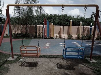 Empty bench in swimming pool against sky