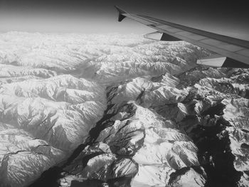 Aerial view of airplane wing over landscape against sky