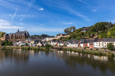 Buildings by river against sky in town