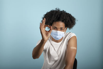 Portrait of young woman standing against blue background