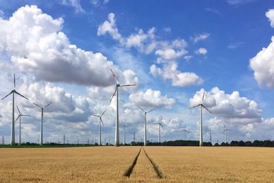 Windmills on field against sky