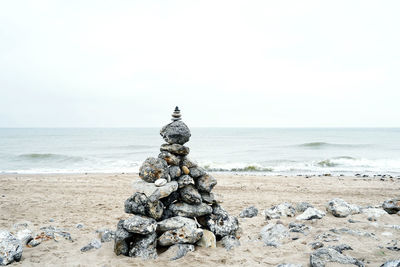 Stack of pebbles on beach against sky