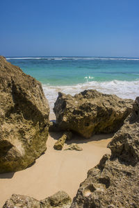 Rocks on beach against clear blue sky