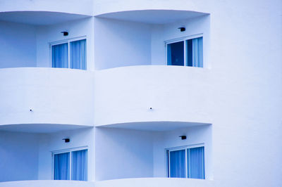 Low angle view of white building with balkony against blue sky