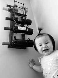 Portrait of smiling girl standing by wine bottles in rack on wall