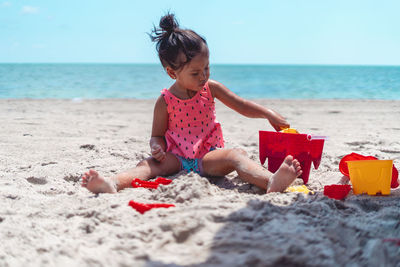 Rear view of boy sitting on sand at beach