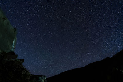 Low angle view of silhouette mountain against sky at night