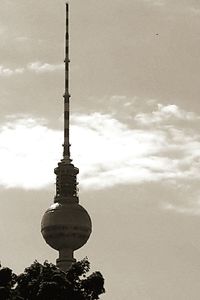 Low angle view of communications tower against cloudy sky