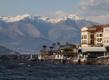 Scenic view of sea by buildings and mountains against sky