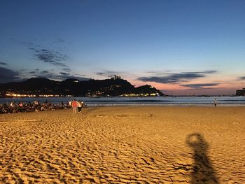 People on beach against sky during sunset