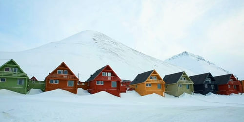 Houses on snowcapped mountain against sky