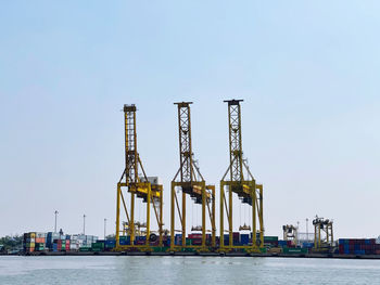 Cranes at commercial dock against clear sky