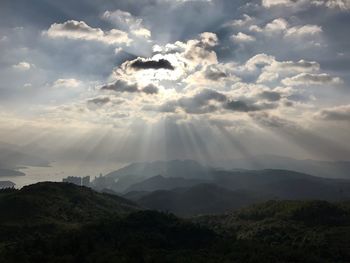 Scenic view of mountains against cloudy sky on sunny day