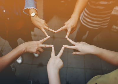 Close-up of people making star shape with hands
