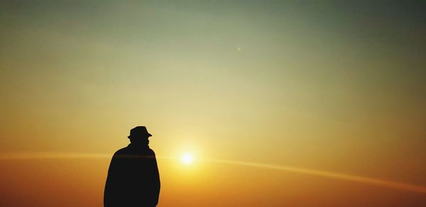 Silhouette man standing against orange sky