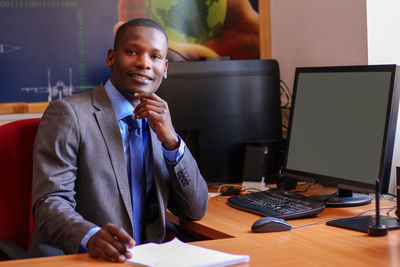 Portrait of man using mobile phone while sitting on table