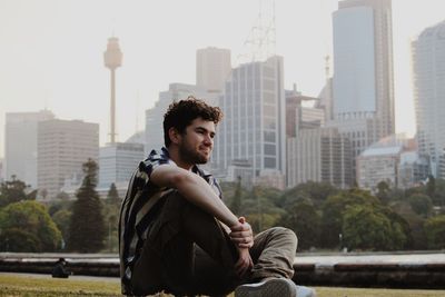 Portrait of young man standing against buildings in city