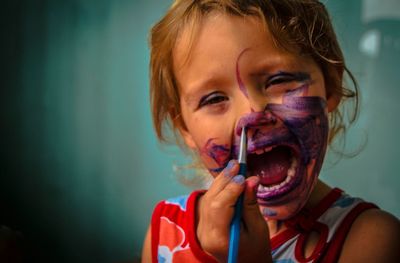 Portrait of girl with mouth open painting her face