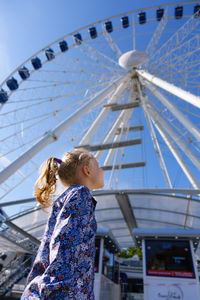 Low angle view of woman with ferris wheel against sky