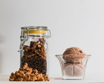 Close-up of cookies in glass jar on table against white background