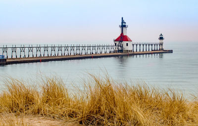 Lighthouse by sea against sky