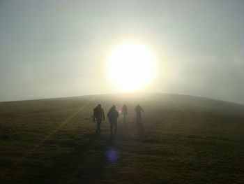 Hikers walking towards sun on hill