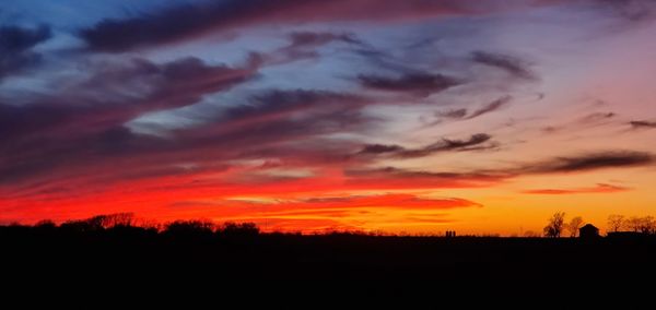 Silhouette landscape against dramatic sky during sunset