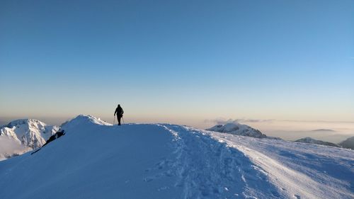 Man on snowcapped mountain against clear sky