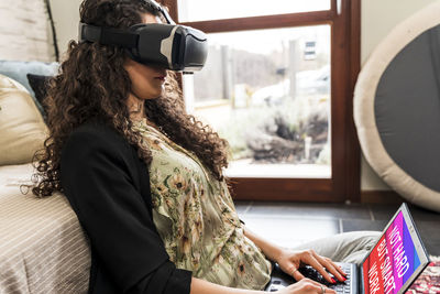 Young woman working at home with augmented reality viewer during restrictions due to the covid-19