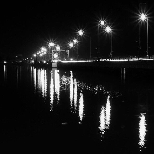 night, water, illuminated, reflection, river, waterfront, pier, street light, bridge - man made structure, silhouette, lake, built structure, connection, tranquility, sky, dark, nature, tranquil scene, outdoors, sea