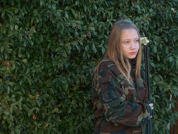 Caucasian blond teen aged soldier girl on a checkpoint holding a gun and wearing military uniform 