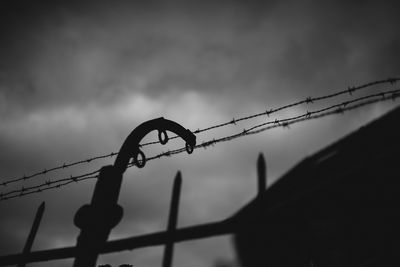 Low angle view of silhouette barbed wire against sky