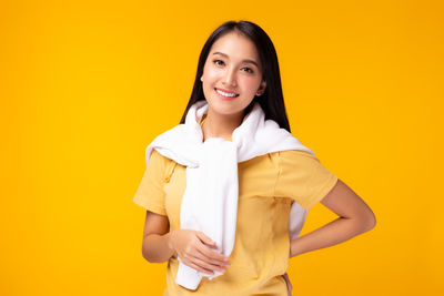 Portrait of a smiling young woman against yellow background