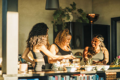 Happy female friends talking to each other while having breakfast at retreat center