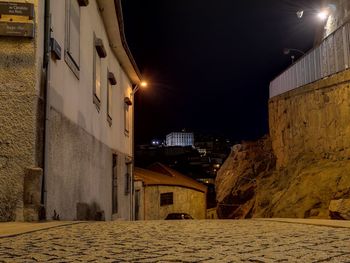 Illuminated street amidst buildings in city at night