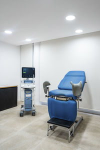 Gynaecologigal chair and medical scanner in illuminated ward