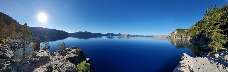 Panoramic view of sea and mountains against clear blue sky