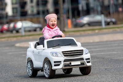 Little girldriving a toy car. little driver, childrens car, concept of road safety, children in car