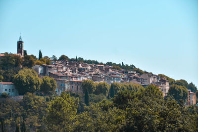 Townscape by trees against blue sky