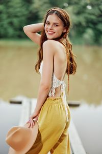 Portrait of young woman standing against trees