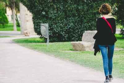 Rear view of woman walking on footpath