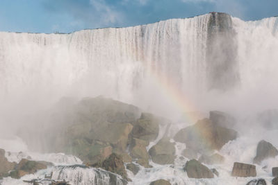 Scenic view of rainbow against waterfall