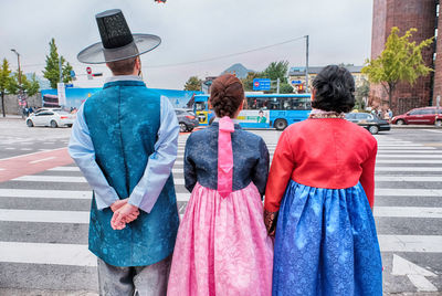 Rear view of family in korean traditional clothing standing on city street