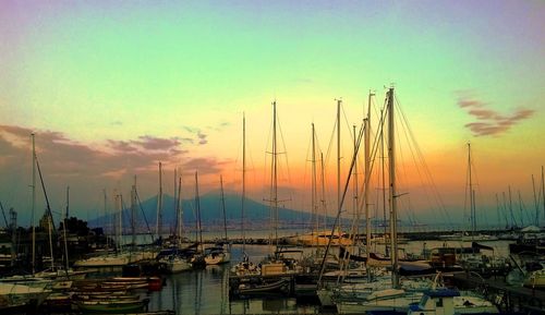 Boats moored at harbor against sky during sunset