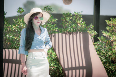 Portrait of woman wearing hat standing against plants